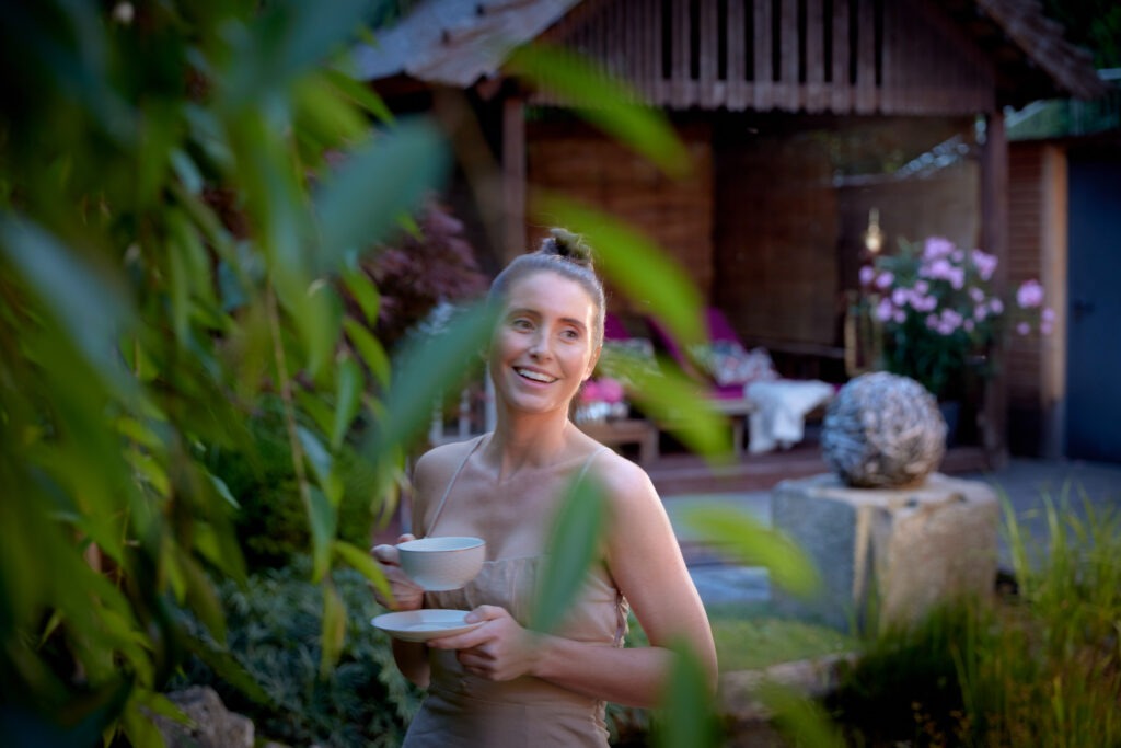 Junge Frau mit Teetasse in Ganesha's Garten